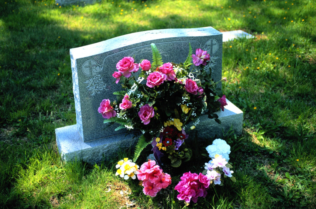 Photo of a grave marker with flowers in front of it.